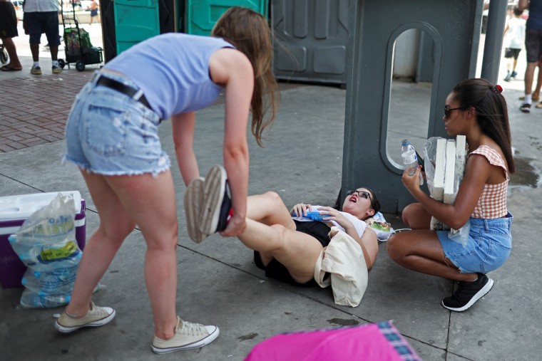 Image: A girl feels sick from high temperatures as she waits outside the stadium for a concert