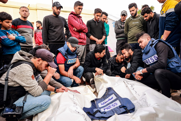 Friends and colleagues mourn the deaths of Hasouna Slim and Sari Mansoor, two Palestinian journalists killed in an Israeli strike, during their funeral in Deir al-Balah.