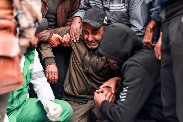 People hold a man as he sobs during the funeral of two Palestinian journalists who were killed in Deir al-Balah.