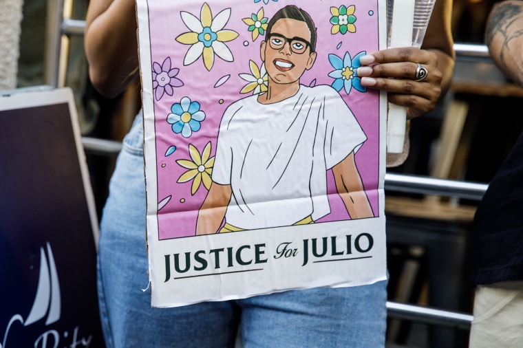 A person hold signs a sign with an illustration of Julio Ramirez