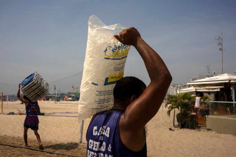 Person carries bag of ice on shoulder. 