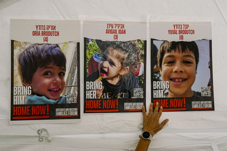 A woman plasters photos of Israeli children from kibbutz Afar Azza, missing and held captive in Gaza, in Tel Aviv, Israel, on Tuesday, Nov. 21, 2023.