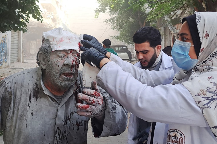 Man covered in blood and dust receives treatment in Gaza