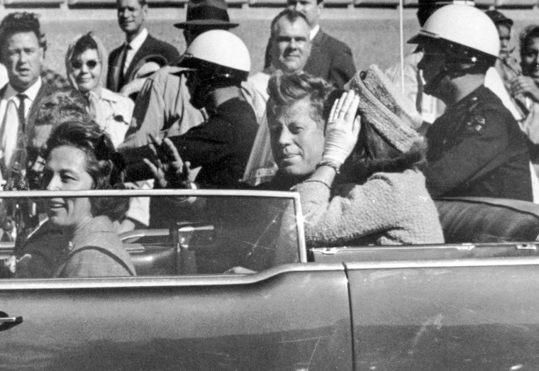 Former President John F. Kennedy waves from his car in a motorcade approximately one minute before he was shot in Dallas, Texas on Nov. 22, 1963. 