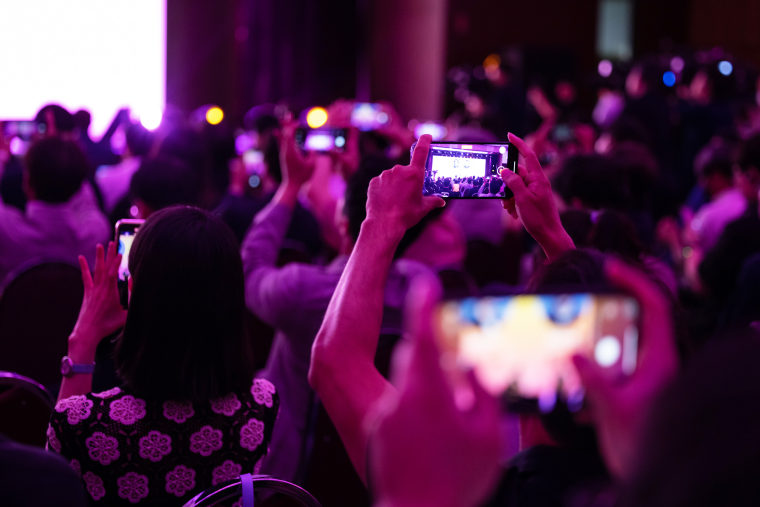 People hold phones into the air to photograph Sam Altman during an event in South Korea