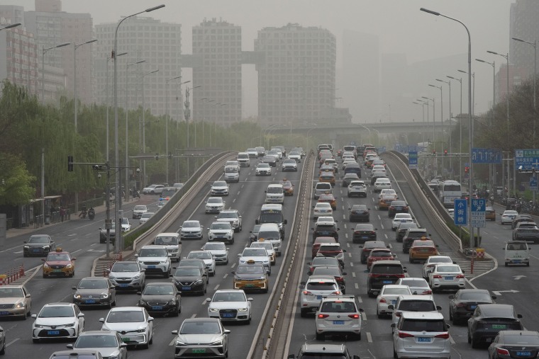 Vehicles travel on a road shrouded in smog during a sandstorm warning in Beijing in April. 