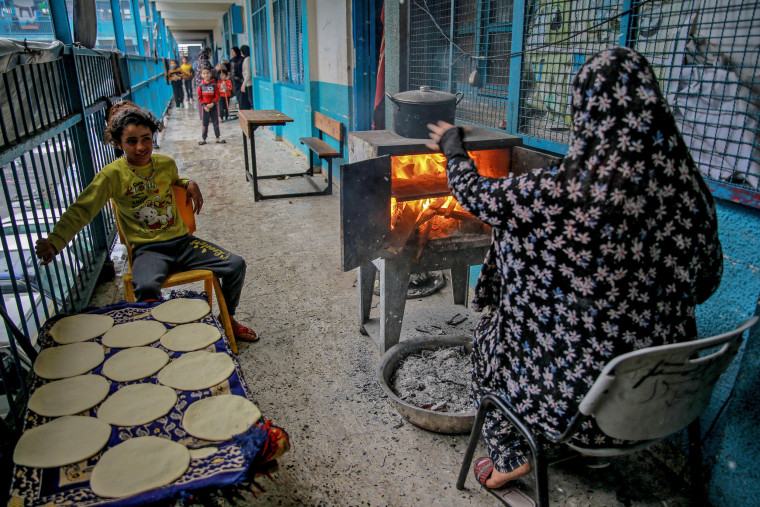 A woman and a child cook bread at a UNWRA school where Palestinians are sheltering in Gaza City on Nov. 27, 2023.