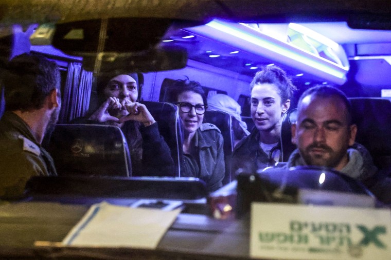 Image: Newly released Israeli hostages sit among soldiers as they arrive inside a van at Ofakim army base 
