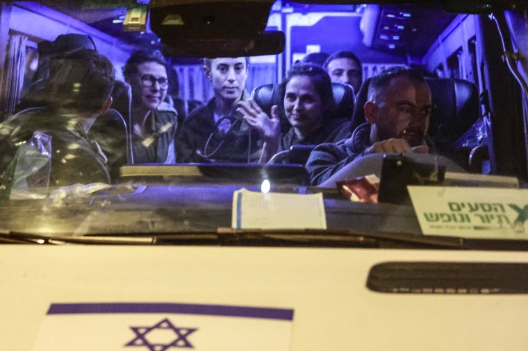 Image: Newly released Israeli hostages sit among soldiers as they arrive inside a van