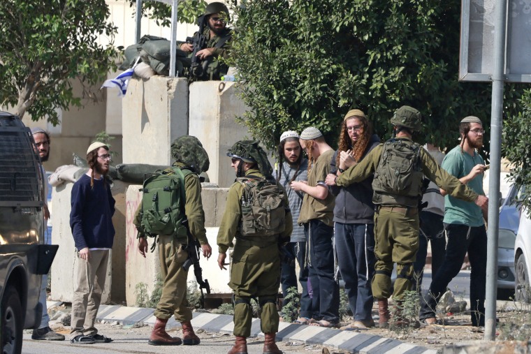 Israeli soldiers restrain Jewish settlers after they stormed the Palestinian West Bank village of Dayr Sharaf, about four miles from the Einav settlement following the fatal shooting of an Israeli man on Nov. 2, 2023. 