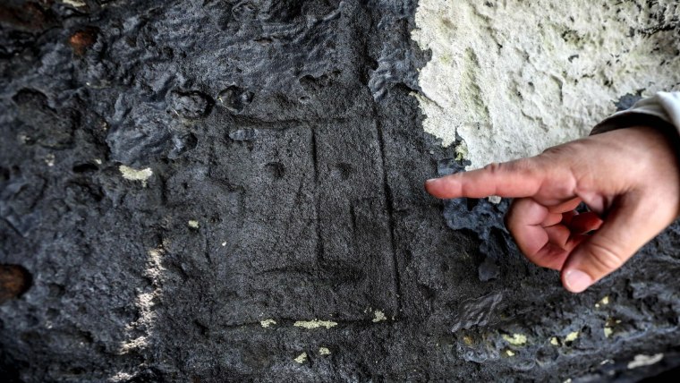 Un arqueólogo apunta a uno de los grabados rupestres sobre piedras avistados por la sequía en el sitio de Ponte das Lajes, en Manaus, Brasil