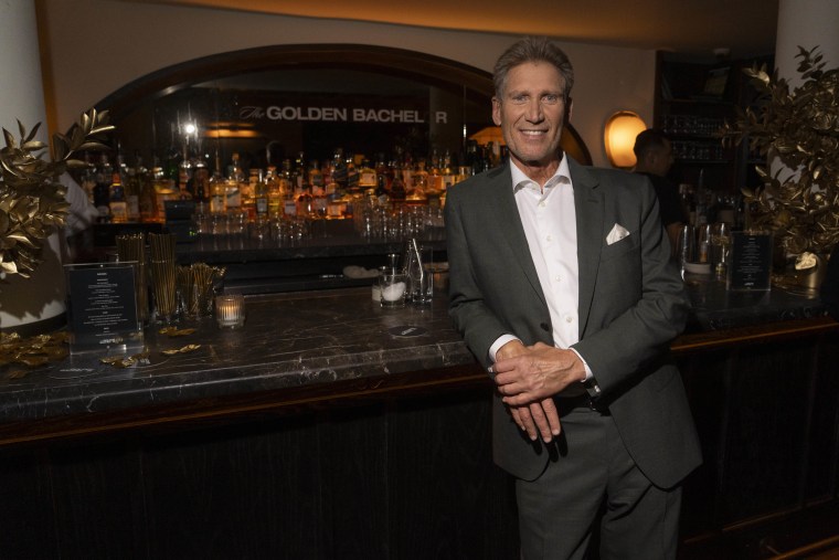 GERRY TURNER stands at a bar in a grey suit with a white shirt.