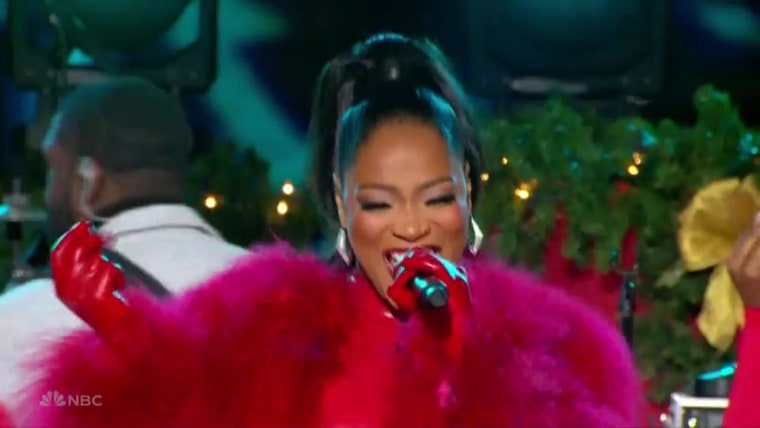 Keke Palmer in red feathers sings with a microphone.