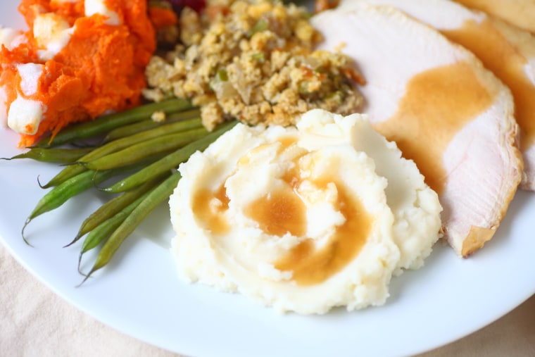Thanksgiving meal with turkey, mashed potatoes, stuffing, green beans and yams with marshmallows and gravy