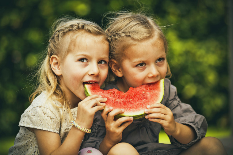 Little twin girls eating watermelon