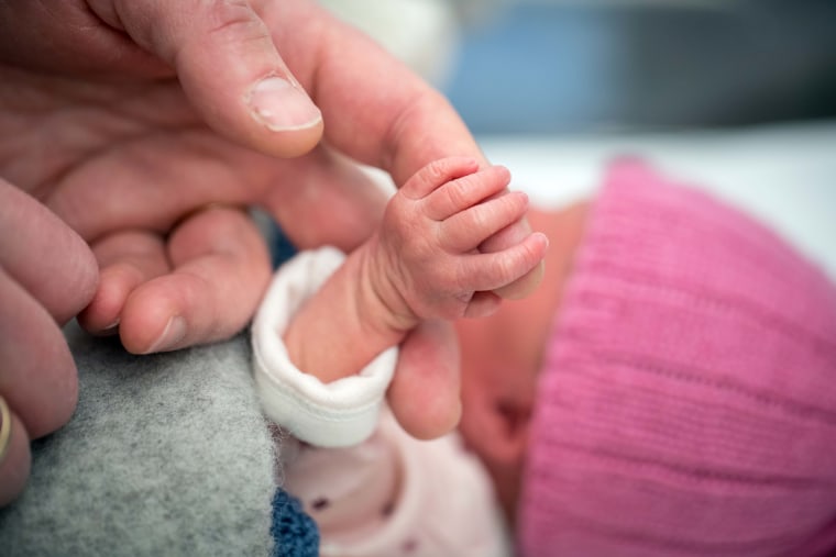 Newborn baby holding on to a finger