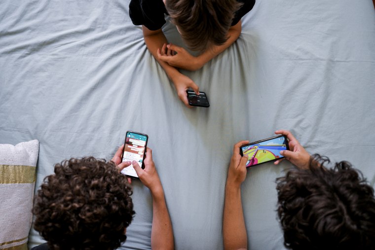 Teenagers browse on their smartphones in Marseille, France on June 27, 2022. 