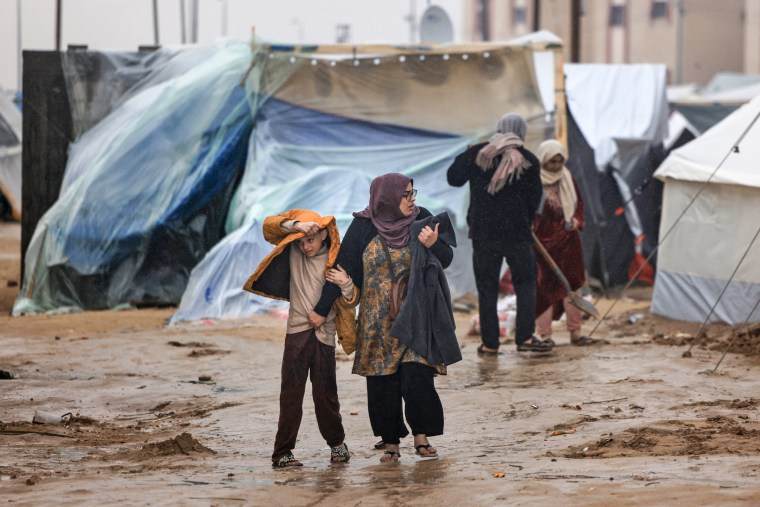 Palestinians walk under the rain at a camp for displaced people in Rafah, in the southern Gaza Strip where most civilians have taken refuge, on Dec. 13, 2023.