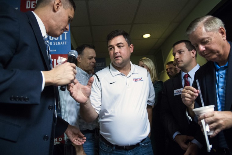 Christian Ziegler reaches for a microphone while surrounded by people