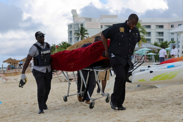 The covered body of a tourist is carried away on a stretcher. following fatal shark attack