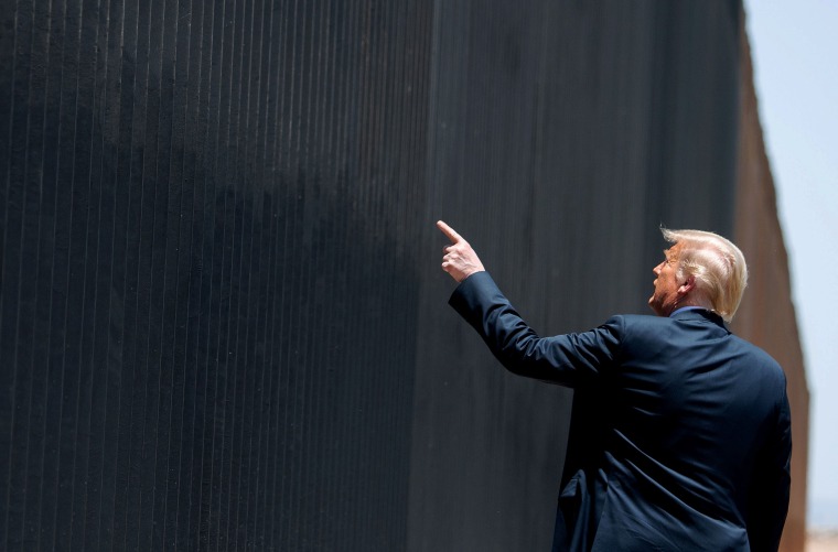 Donald Trump points to the border wall.