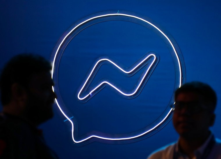 People converse in front of a Facebook messenger logo during a Meta event in Mumbai, India