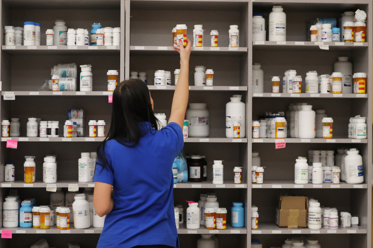 A pharmacy technician grabs a bottle of drugs off a shelf in Midvale, Utah in 2018.