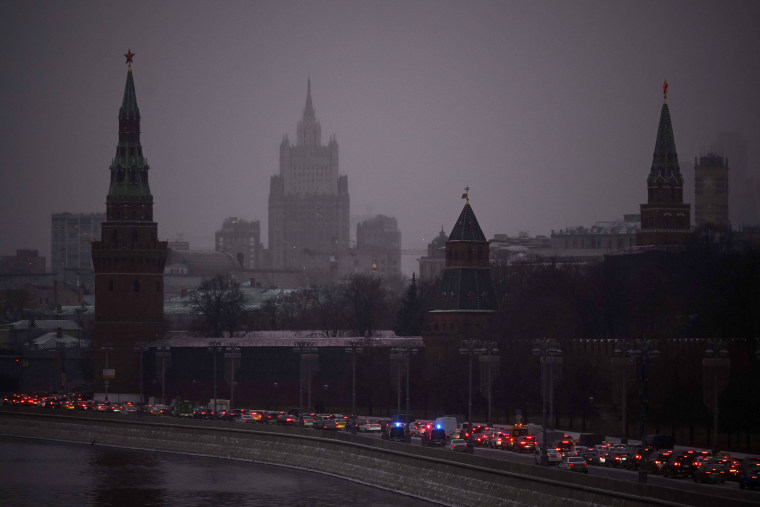 Cars slowly move along an embankment of the Moskva river past the Kremlin
