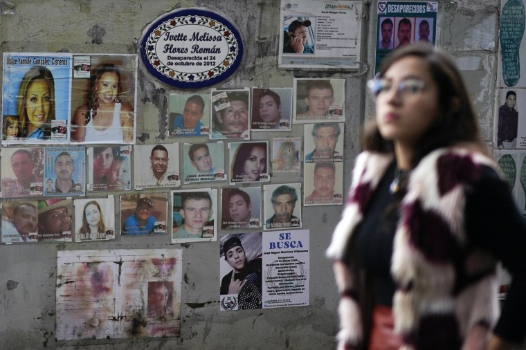 Image: A woman passes in front of photographs of missing persons 