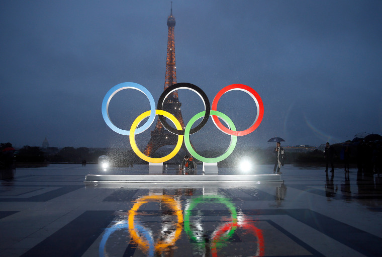 People walk in the rain The unveiling of the Olympic rings in Paris.