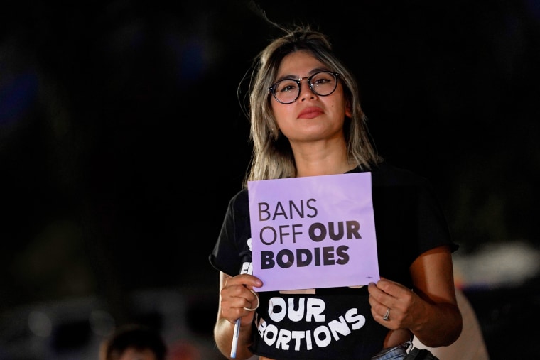 A protester holds a sign that reads, "Bans off our bodies."