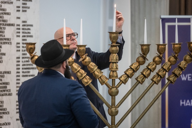 Rabbi Shalom Ber Stambler and deputy speaker Piotr Zgorzelski light Hanukkah candles on a menorah a few minutes before far-right lawmaker Grzegorz Braun used a fire extinguisher to put them out in the parliament lobby  in Warsaw.