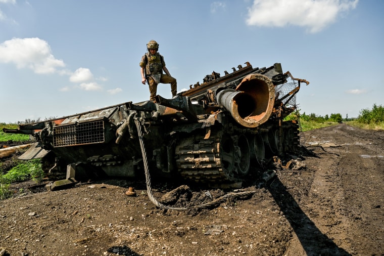 A press officer stands on top of a destroyed Russian military vehicle in Novodarivka village in Ukraine