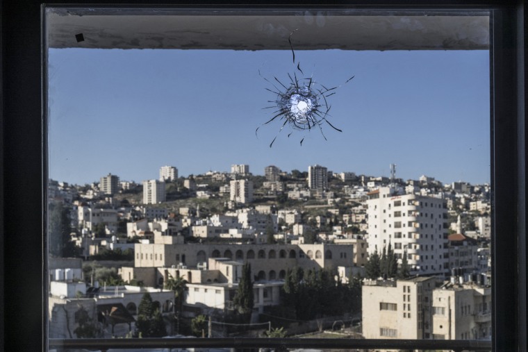 A hole from a stray bullet is seen in the window of a hotel room in Jenin in the occupied West Bank on Dec. 14, 2023.