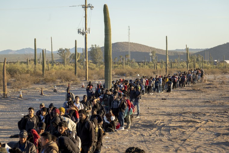 Immigrants line up at a remote U.S. Border Patrol processing center after crossing the U.S.-Mexico border in Lukeville, Ariz.