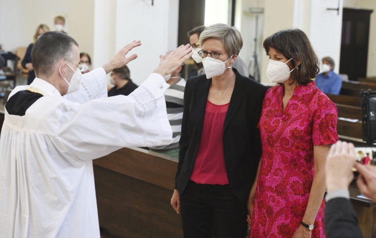 Vicar Wolfgang Rothe blesses Christine Walter, center, and Almut Muenster in St Benedict's Church in Munich, on May 9, 2021. 