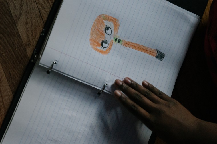 Image: Girl looking through a binder with drawings.