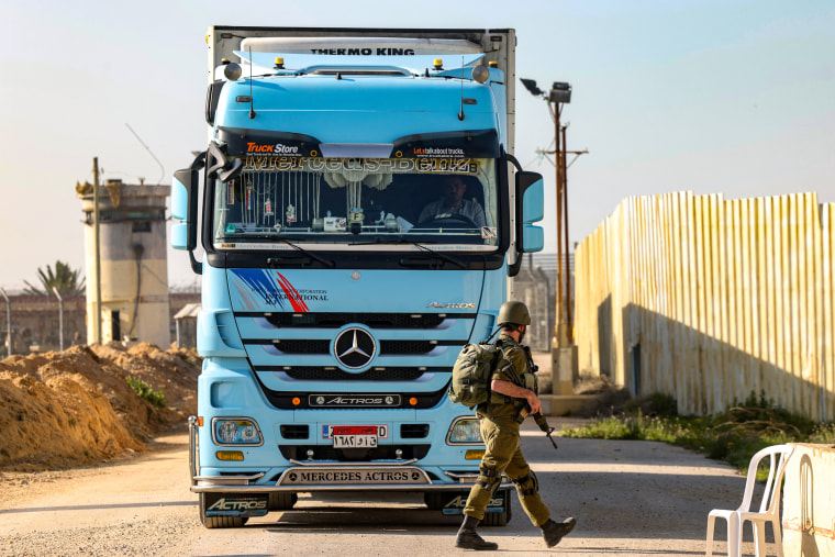 An Israeli soldier walks past a truck carrying humanitarian aid at the Israeli side of the Kerem Shalom border crossing with the southern Gaza Strip on Dec. 19, 2023.
