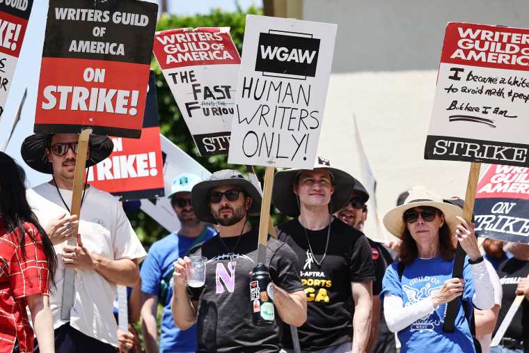 A sign reads 'Human Writers Only!' as striking Writers Guild of America workers picket outside Paramount Studios.