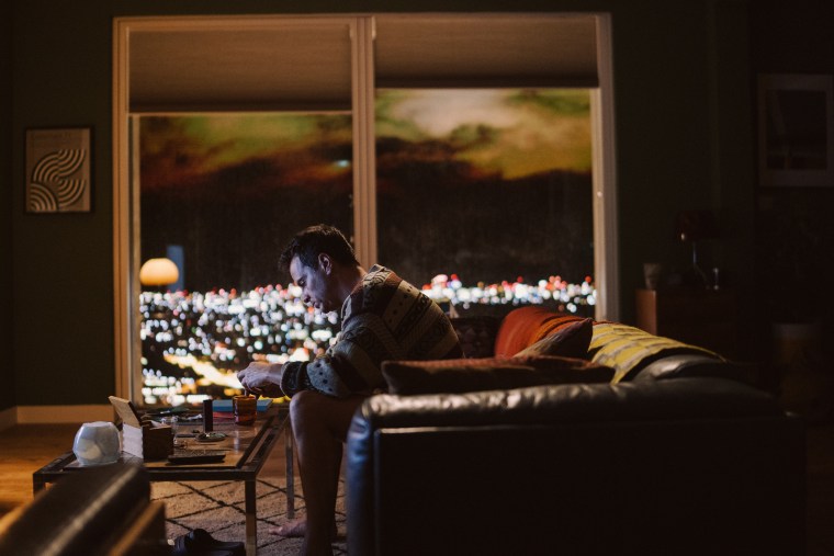 Andrew Scott sits alone on a couch in a scene from "All of Us Strangers."