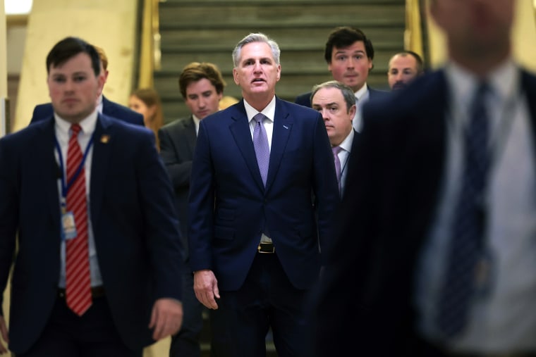 Kevin McCarthy walks through a hallway at the Capitol, flanked by staffers
