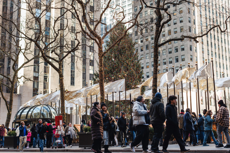 People walk passed the Rockefeller Christmas Tree.