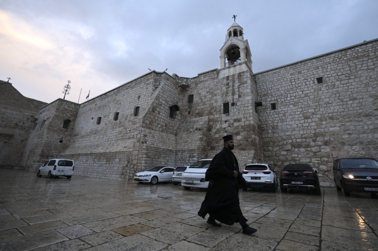 A priest walks in the empty square in front of the Church of the Nativity in the city of Bethlehem