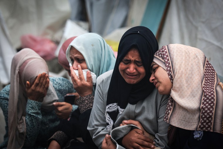 Women cry as they mourn their relatives.