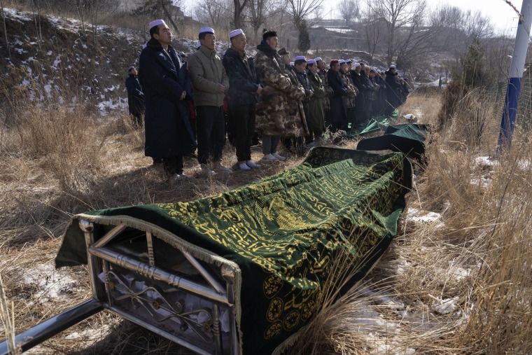 Ma Lianqiang, left, stands near the body of his wife, Han Suofeiya, before her burial in northwestern China's Gansu province, Dec. 20, 2023. His wife was killed in the earthquake.