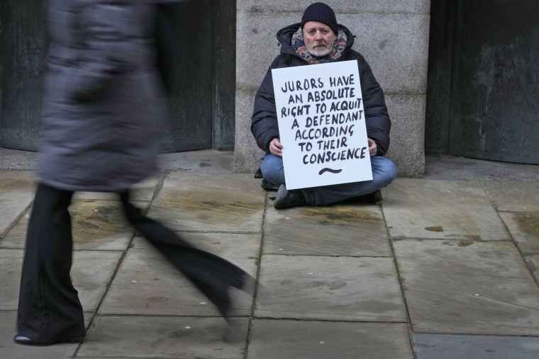 A demonstrator holds a banner outside The Old Bailey, the Central Criminal Court of England and Wales, in London, on Dec. 4, 2023. 