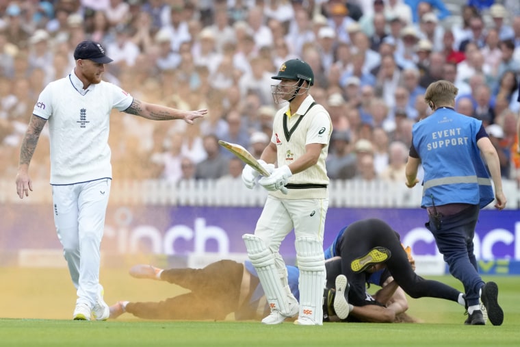 England's Ben Stokes, left, and Australia's David Warner react as a "Just Stop Oil" protester is apprehended after throwing colored powder on the pitch at Lord's Cricket Ground in London on June 28, 2023.