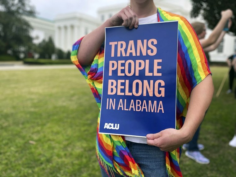 A person holds up a sign reading "Trans People Belong in Alabama" at a rally outside the Alabama Statehouse in Montgomery on March 31. 