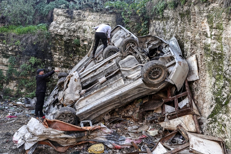 Palestinians inspect the remains of overturned vehicles in the aftermath of an Israeli raid in the Nur Shams camp for Palestinian refugees, near the northern city of Tulkarm in the occupied West Bank on Dec. 27, 2023. 