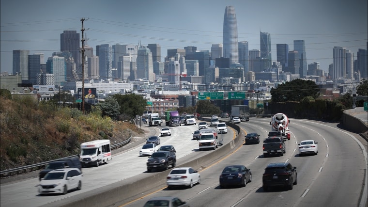 Vehicle traffic passes in front of the San Francisco skyline.